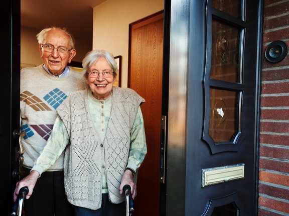 elderly couple opening the front door